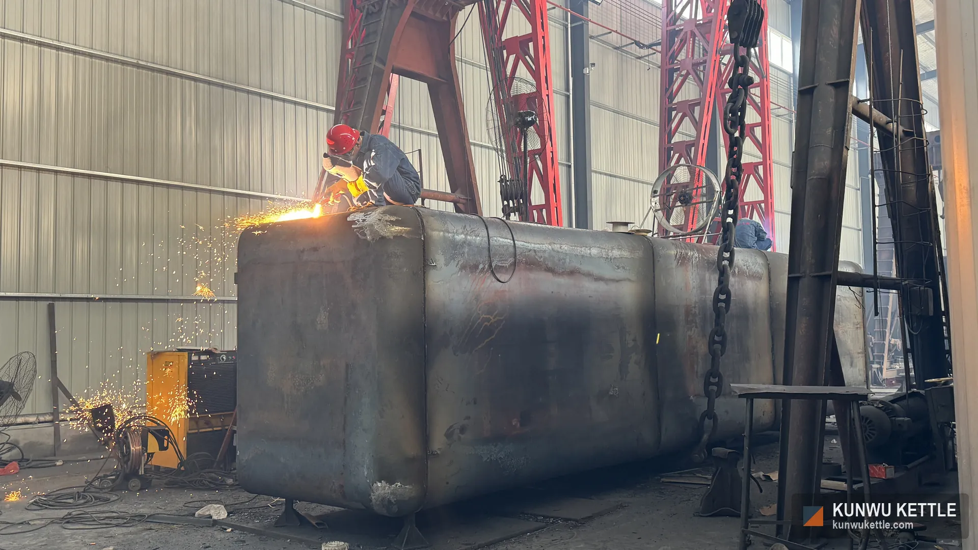 Welder working on a full rounded corner galvanizing kettle shell before painting